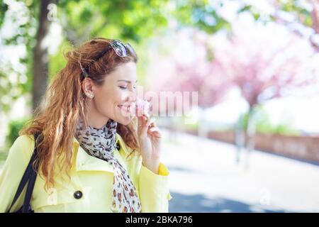 Giovane allegra donna che odora ciliegia fioritura nel parco in primavera Foto Stock