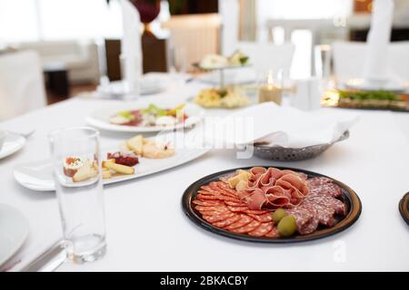 Vassoio per alimenti con deliziosi salami, pezzi di fette di prosciutto, salsicce, pomodori, insalata e vegetali - piatto a base di carne con selezione - Taglio di salsiccia e cura Foto Stock