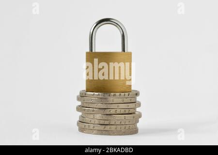 Lucchetto su pila di monete su sfondo bianco - concetto di sicurezza finanziaria Foto Stock
