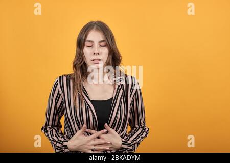 Ragazza è piegata, grimaces da dolore nello stomaco o nel ventre, mani di tenuta a irritare Foto Stock