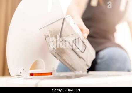 Donna pulisce il cestino automatico robot aspirapolvere Foto stock - Alamy