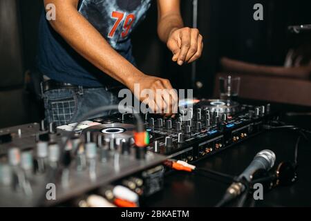 Primo piano della mano del DJ che suona la musica al giradischi su un festival di festa - Ritratto di DJ mixer audio in un Beach club sopra la folla che balla e avendo f Foto Stock