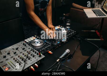 Primo piano della mano del DJ che suona la musica al giradischi su un festival di festa - Ritratto di DJ mixer audio in un Beach club sopra la folla che balla e avendo f Foto Stock