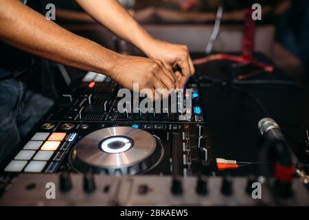 Primo piano della mano del DJ che suona la musica al giradischi su un festival di festa - Ritratto di DJ mixer audio in un Beach club sopra la folla che balla e avendo f Foto Stock