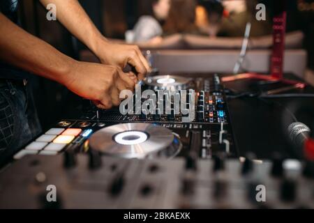 Primo piano della mano del DJ che suona la musica al giradischi su un festival di festa - Ritratto di DJ mixer audio in un Beach club sopra la folla che balla e avendo f Foto Stock