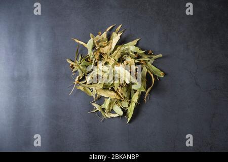 Tè Linden su sfondo di pietra. Ingredienti aromatici, salutari e secchi del tè alle erbe. Antiossidante e protettore contro il freddo infettivo. Disposizione piatta Foto Stock