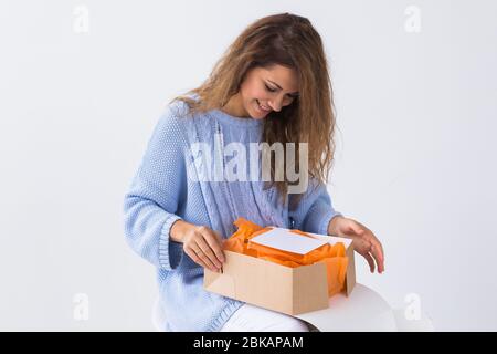 Shopping online, consegna e concetto di moda - Donna seduta a casa apertura di acquisto di abbigliamento online Foto Stock