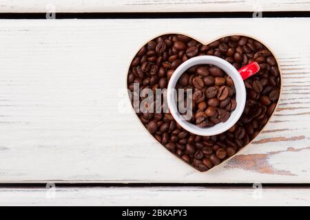 Forma a tazza e cuore riempita con grani di caffè tostati. Foto Stock