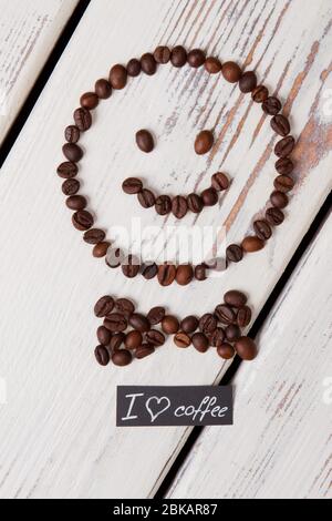 Faccina sorridente con cravatta a fiocco in chicchi di caffè. Foto Stock