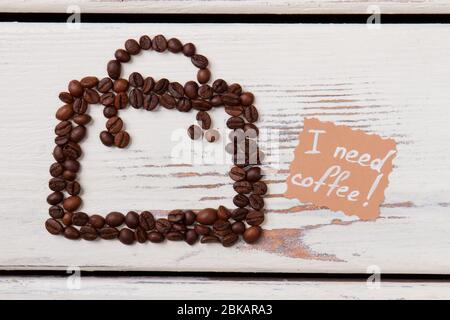 Caffè in chicchi a forma di vaso su legno bianco. Foto Stock