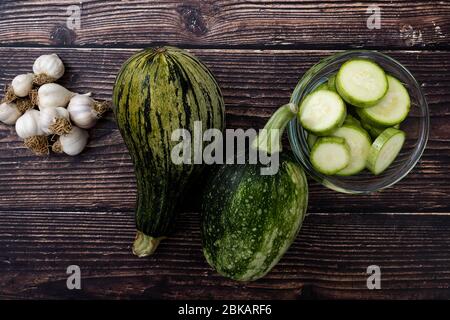 Vista dall'alto delle zucchine e delle zucchine a fette su sfondo di legno. Verdure fresche e biologiche da giardino. Foto Stock