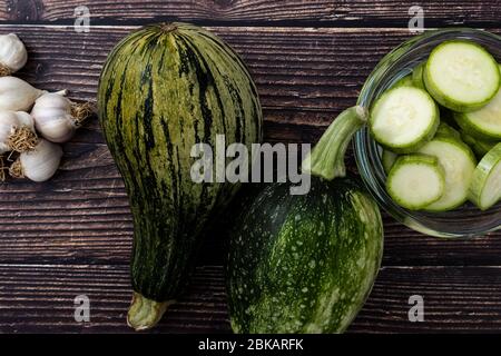 Vista dall'alto delle zucchine e delle zucchine a fette su sfondo di legno. Verdure fresche e biologiche da giardino. Foto Stock