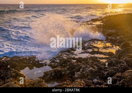 Grandi onde che si schiantano contro le rocce al tramonto, Grand Cayman Blowhole Foto Stock