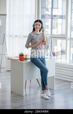 Donna dai capelli scuri in cuffia per ascoltare qualcosa Foto Stock