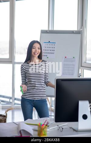 Tutor dai capelli scuri in una camicia a righe che conduce lezioni online Foto Stock