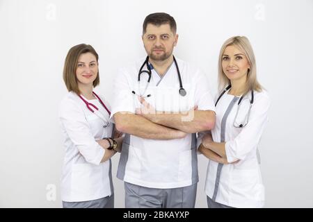Giovane squadra di medici con stetoscopi in uniforme moderna, ritratto contro una parete bianca. Foto Stock
