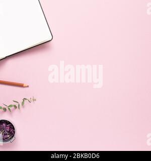 Luogo di lavoro e studio, taccuino vuoto e matita colorata con fiori secchi su sfondo rosa. Piano, vista dall'alto, spazio copia Foto Stock