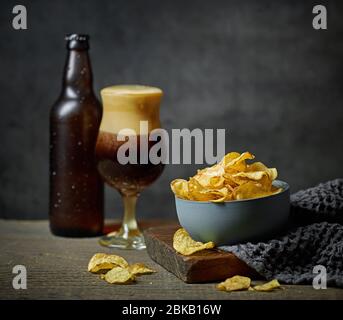 ciotola di patatine e birra su tavolo di legno Foto Stock