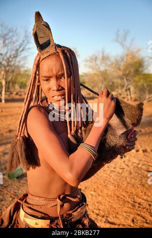 Batwa ragazza in abito tradizionale pettinando i capelli al tramonto. Foto Stock