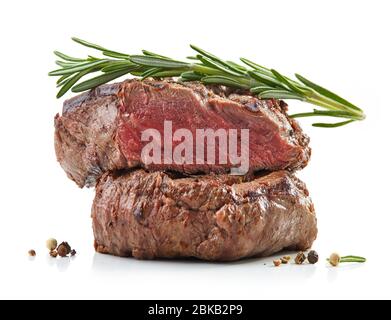 pila di due succulente bistecche di filetto di manzo alla griglia con rosmarino isolato su sfondo bianco, fuoco selettivo Foto Stock