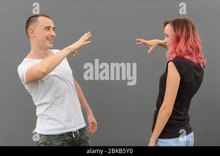 Ritratto di coppia felice facendo stretta di mano insieme contro il muro grigio Foto Stock