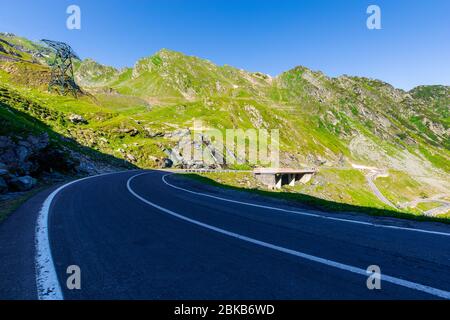 strada di montagna tortuosa in una giornata di sole. autostrada vuota che attraversa la valle. vista aperta in lontananza. grande viaggio europeo in estate concetto. Foto Stock