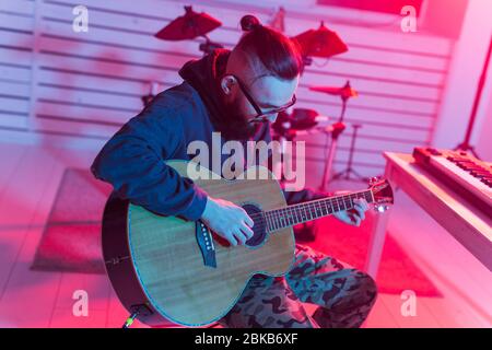 Crea musica e un concetto di studio di registrazione - Guitarist uomo buffo bearded che registra la traccia di chitarra elettrica in studio domestico Foto Stock