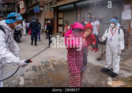 Kathmandu, Nepal. 3 maggio 2020. Una madre ed il suo bambino che sono spruzzati con disinfettante come precauzione contro la diffusione di coronavirus durante i residenti pandemic.Local che si offrono volontariamente nella loro comunità per disinfettare i compagni residenti in mezzo alla situazione nazionale di blocco e di minaccia del virus corona. Credit: Sunil Pradhan/SOPA Images/ZUMA Wire/Alamy Live News Foto Stock