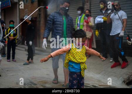 Kathmandu, Nepal. 3 maggio 2020. Un bambino che viene spruzzato con disinfettante come precauzione contro la diffusione di coronavirus durante la pandemic.Local residenti volontariato nella loro comunità di disinfettare i compagni residenti in mezzo alla situazione nazionale di blocco e di minaccia del virus corona. Credit: Sunil Pradhan/SOPA Images/ZUMA Wire/Alamy Live News Foto Stock