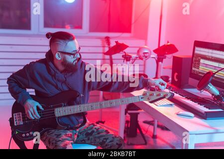 Crea musica e un concept di studio di registrazione - chitarrista Bearded man che registra una traccia di chitarra elettrica in studio domestico Foto Stock