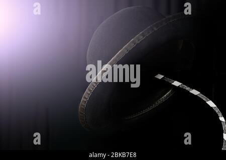 Mimo cappello su un appendiabiti su sfondo nero illuminato da luce drammatica. Foto Stock