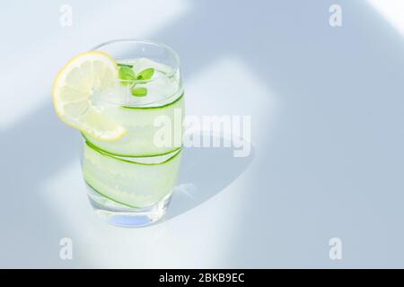 Bicchiere d'acqua con limone, ghiaccio e cetriolo isolato. Spazio copia. Foto Stock
