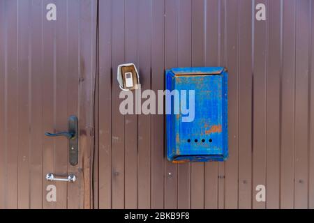 Vecchia casella postale blu appesa su una recinzione di metallo marrone. Foto Stock