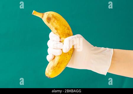 Guanti di gomma bianca con banana. Coronavirus. Spazio di copia. Foto Stock