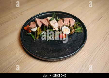 carne con asparagi, pomodoro, uova su grattugia nera su un tavolo di legno Foto Stock