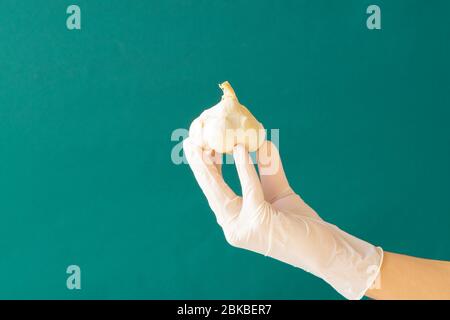 Guanti di gomma bianca per tenere l'aglio. Coronavirus. Spazio di copia. Foto Stock