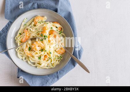 Tagliatelle di pasta italiana con salsa cremosa e gamberi. Spazio di copia. Foto Stock