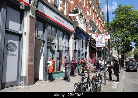 Coda fuori dall'ufficio postale di Islington, in Upper Street, nel blocco dei pandmeici del coronavirus, nel nord di Londra, Regno Unito Foto Stock