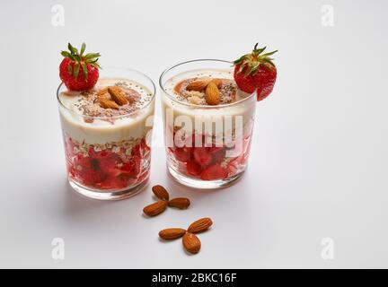 Fragole fresche con yogurt alla soia, fiocchi d'avena, mandorle, marmellata di frutta rossa, farina di cocco e semi di chia. Foto Stock