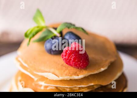 Mucchio di pancake con mirtilli e lamponi per colazione su tavolo di legno. Foto Stock