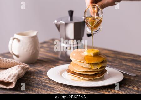 Sciroppo d'acero che versa su una pila di mini pancake. Foto Stock