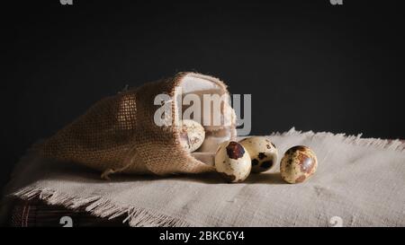 ancora vita, uova di quaglia con un sacchetto su un tessuto grigio su uno sfondo scuro Foto Stock
