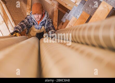 Tema industriale. Tubazioni di ventilazione per aria residenziale preparate da un tecnico caucasico. Qualità dell'aria domestica. Foto Stock