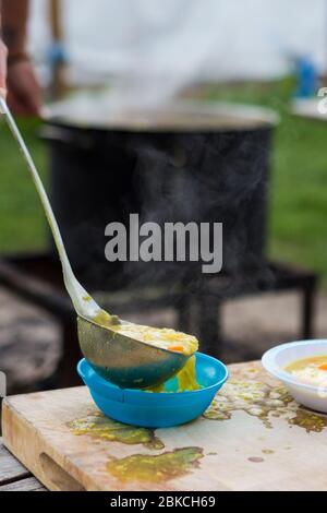 Zuppa gratuita preparata al fuoco, servita in una serata estiva al Wowo's, un campeggio familiare in Sussex Foto Stock