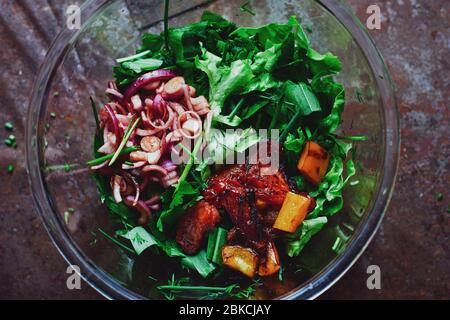Ingredienti freschi utili per cetrioli da insalata, pomodori, peperoni e foglie in una ciotola di vetro Foto Stock