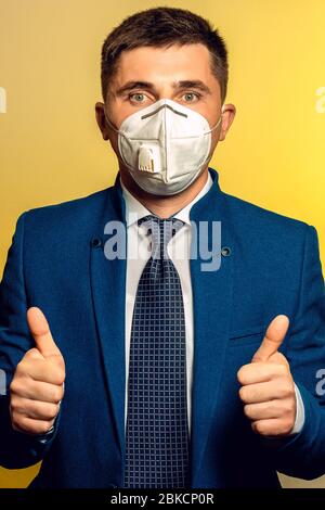Uomo forte, uomo d'affari in cravatta e maschera medica dimostra la fiducia nel lavoro nel coronavirus pandemico. Mostra un pollice su di entrambe le mani 2021 Foto Stock
