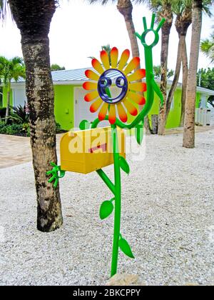 Una casella postale degli Stati Uniti che è tenuta da un fiore smiley-faccia artisticamente fatto di metallo dipinto brillantemente cattura l'occhio della gente che passa da questa casa colorata su Casey Key nella contea di Sarasota lungo la costa del Golfo della Florida, Stati Uniti. È il lavoro creativo di Floridian Scott Gerber, che ha realizzato la sua prima figura sorridente del bastone da tubi di alluminio di scarto nel 2010. Da allora la sua azienda Tube Dude ha venduto migliaia di sculture stravaganti realizzate su misura in vari disegni a clienti di tutto il mondo. Foto Stock