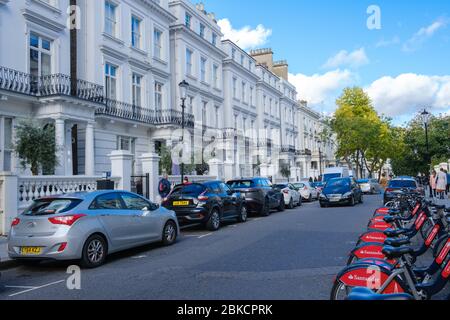 Bici Santander rosse in affitto parcheggiate fuori case bianche a South End di Pembridge Gardens, di fronte a North, Notting Hill, West London, Inghilterra, Regno Unito Foto Stock