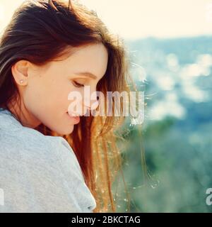 vista laterale di una ragazza sorridente su uno sfondo naturale. primo piano Foto Stock