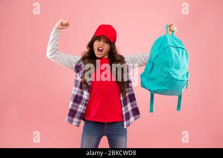 Potente bambino. Trasporto di oggetti in zaino. Scopri come montare correttamente lo zaino. Zaino per bambini alla moda ragazza. Utile accessorio di moda. Scolaretta rossa cappuccio capelli lunghi con zaino scuola. Foto Stock